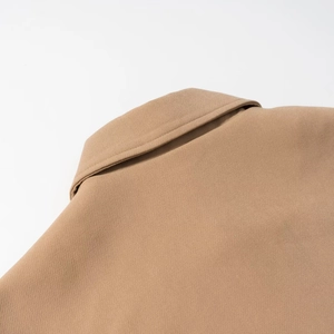 Gros plan du col à revers camel montrant la texture du tissu tissé et la couture