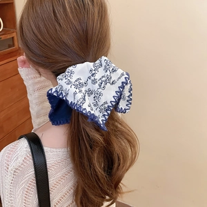 Close-up detail of white fabric headband with blue floral prints and wavy stitched edges