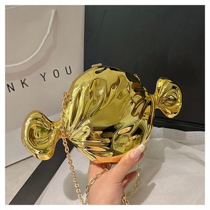 Close-up of a gold candy-shaped hard shell clutch bag with a metal chain strap