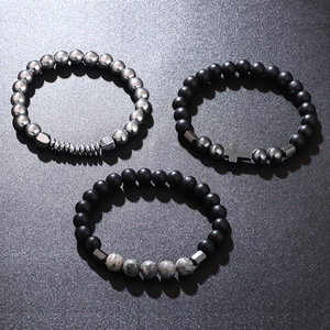 Three beaded bracelets with silver metal cross and matte black stone on dark background