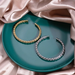 Detail view of gold and silver knotted metal cuffs on luxury satin and green plate