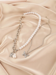 Close-up of layered baroque pearl necklace with butterfly charm and embossed metal pendant
