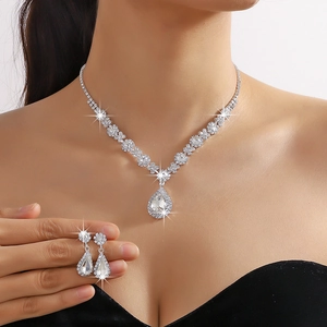 Model wearing a pear-cut crystal necklace and earrings set with shimmering silver plating
