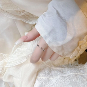 Detail of twisted S925 silver ring with black resin stones on light lace fabric
