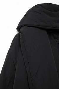 Detailaufnahme einer schwarzen Steppjacke mit matter Stoffstruktur und Knopfverschluss
