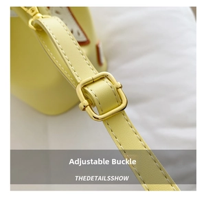 Detail of adjustable metal buckle and lychee textured leather strap on yellow bucket bag