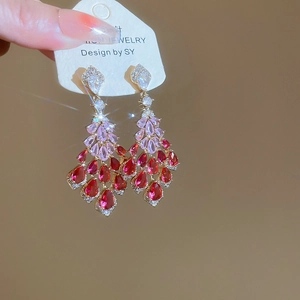 Close-up of heart-shaped zircon earrings with pink and red tassel droplet crystals