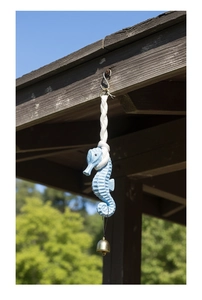 Close-up of light blue sea horse ornament with brass bell hanging outdoors