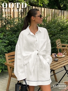 Détail du chemisier en lin blanc noué et du short avec bordures contrastées noires