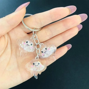 Hand holding three-piece cartoon jellyfish resin charms with glitter on a keychain