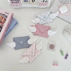 Cute plush envelope coin purses with angel wings in four pastel colors on a desk