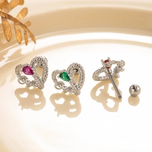 Three silver heart earrings with pink, green and red gems on a ceramic tray