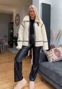 Detail view of a creamy faux shearling jacket with contrasting black trim and lapels