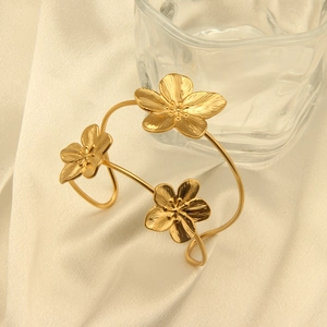 Detail of 18k gold plated stainless steel flower bracelet on elegant beige silk background