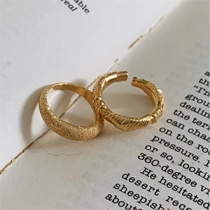Close-up of gold knotted and spiral rings displayed on a vintage open book page