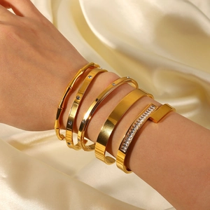 Stacked gold stainless steel bracelets with zirconia inlay on a luxury silk background