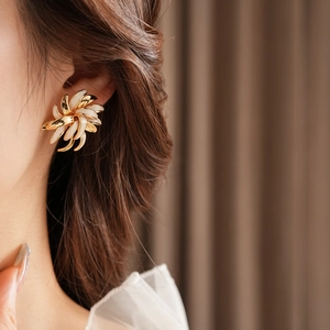 Close-up of vintage gold-plated enamel daisy earring worn on ear with soft lighting