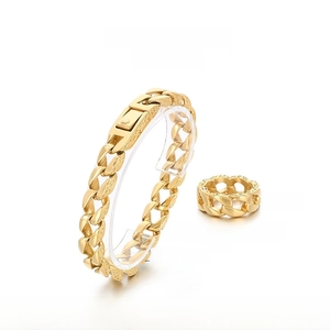 Detail of gold stainless steel Cuban chain bracelet and ring set with engraved textures