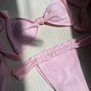 Detailed view of pale pink bikini set featuring a knotted top and side-tie bottoms on waffle fabric