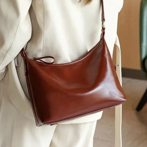 Close-up of luxury reddish brown leather hobo bag with adjustable metal buckle strap