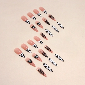 Long stiletto press-on nails with black cow print, snake motifs and heart eye patterns