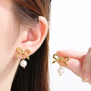 Elegant bow and pearl stainless steel stud earrings shown on model for a classic look