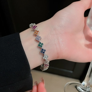 Detailed close-up of a silver-toned clover bracelet with colorful zircons on a model's wrist