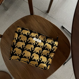 Close-up of golden elephant jacquard pattern on a black fabric pouch with zipper