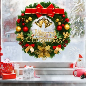 Close-up of Christmas wreath with red bow and bells hanging on a snowy windowpane