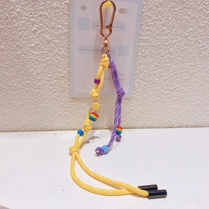 Détail du cordon tressé jaune et violet avec pendentif smiley et perles arc-en-ciel