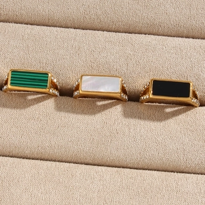 Three gold vintage rings with green, white, and black stones in a beige velvet box