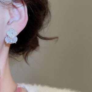 Gros plan d'une élégante boucle d'oreille trèfle en zircon portée par un mannequin de profil