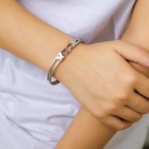 Detailed view of silver butterfly bangle with mother of pearl inlay on model's wrist