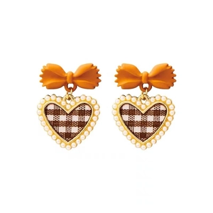 Macro view of bow heart earrings with gingham pattern and pearl bead trim details