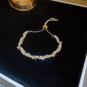 Detailed view of adjustable gold bracelet with rectangular crystals and white pearls