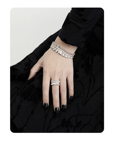 Detailed view of silver S925 ring and cuff with pleated texture on black fabric