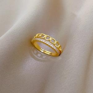 Detail of gold chain ring with micro-paved zircons on elegant champagne silk fabric