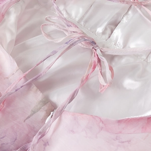Detailopname van roze organza jurk met striksluiting aan de achterkant en satijntextuur