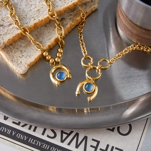 Golden titanium steel chain necklace with U-shaped blue resin gemstone pendant on tray