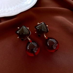 Macro detail of amber resin drop earrings with gold-tone metal claws on silk