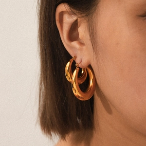 Polished 18K gold plated hollow chunky hoop earrings worn by a model in a fashion style