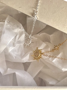Close-up of gold and silver sunburst star necklaces on soft pleated silk paper