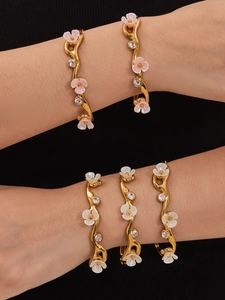 Detail of gold C-shaped flower cuff bracelet with pink and white zircon floral accents