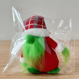 Detail of Christmas gnome with green fur beard and red checkered hat on wooden table