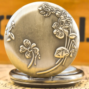 Macro detail of antique bronze pocket watch cover with embossed floral relief patterns