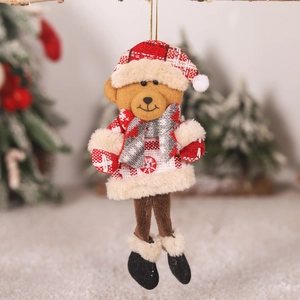 Close-up of a plush Christmas bear ornament with red plaid details hanging on a tree