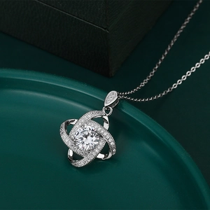 Detailed view of silver knot pendant with a 2-carat zircon center stone on dark green tray