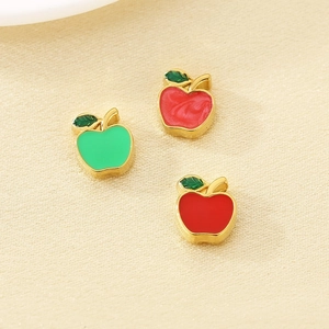 Detail of red and green enamel apple charms in gold-plated stainless steel for jewelry