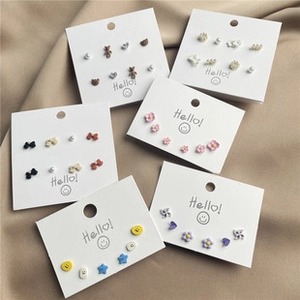 Detail shot of 6-piece cute earring set featuring flowers, bears, and stars on cream fabric