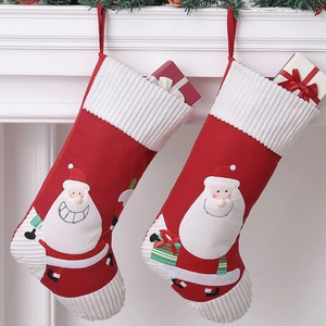 Large Christmas stockings with Santa embroidery hanging on a white fireplace mantle
